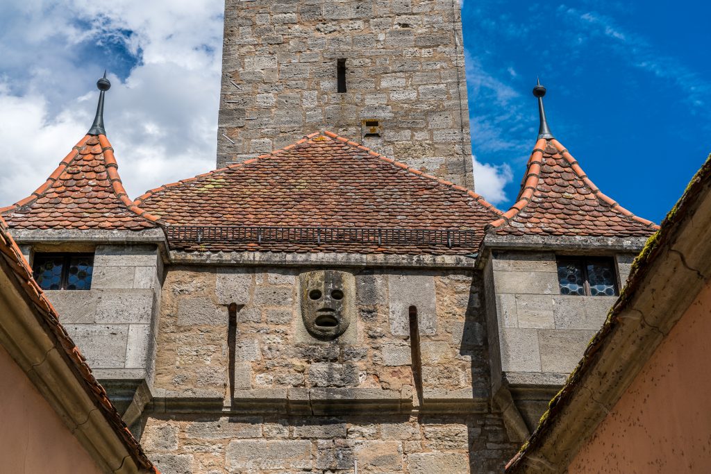 Máscara no alto do portão Burgtor em Rothenburg
